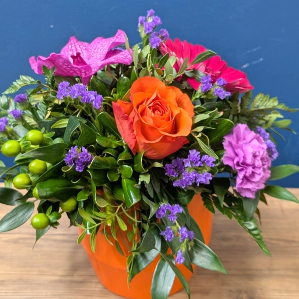 Vibrant summer flower arrangement in orange ceramic pot with pink purple and orange flowers