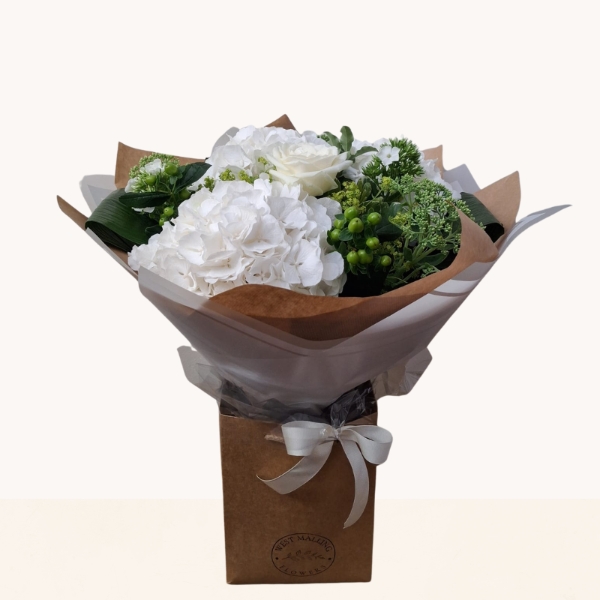 Luxury white hydrangea bouquet with seasonal white flowers and fresh green foliage.