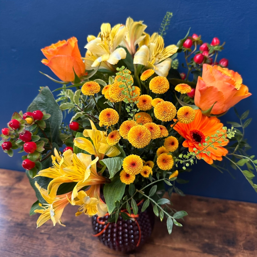 Bright spring vase arrangement with orange yellow and red seasonal flowers in a decorative vase