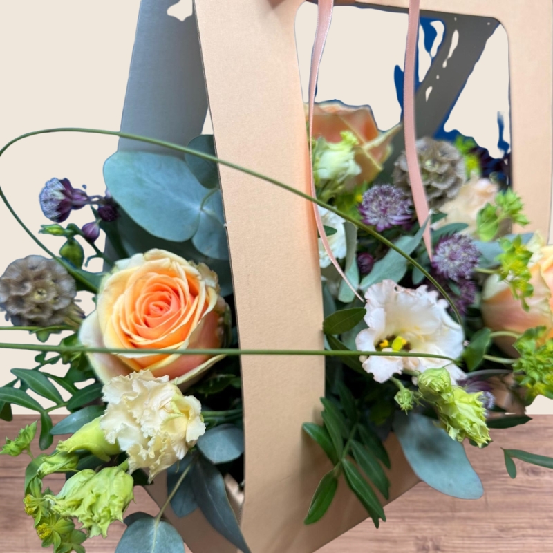Birthday living flower card arrangement with peach roses, cream lisianthus and seasonal flowers presented in a card-style floral gift.