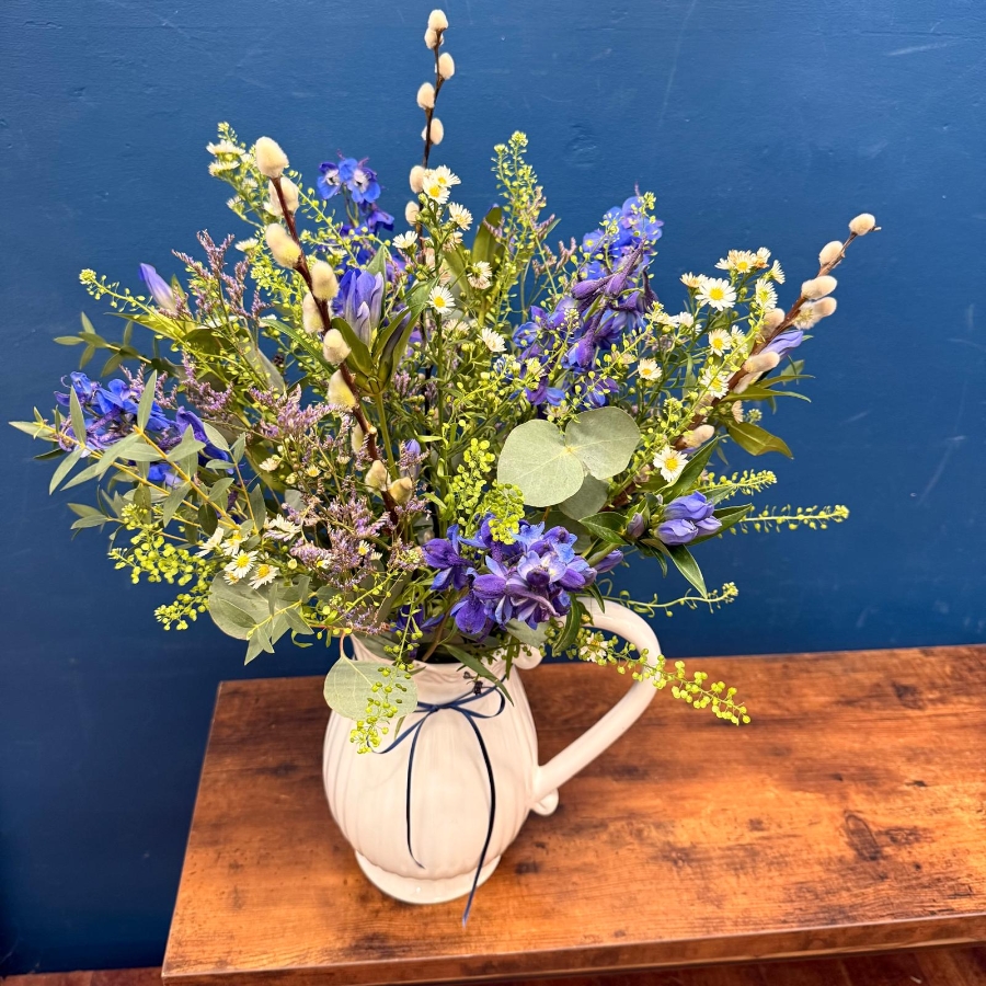 Spring flowers arranged in a white ceramic jug with pink and lilac seasonal flowers