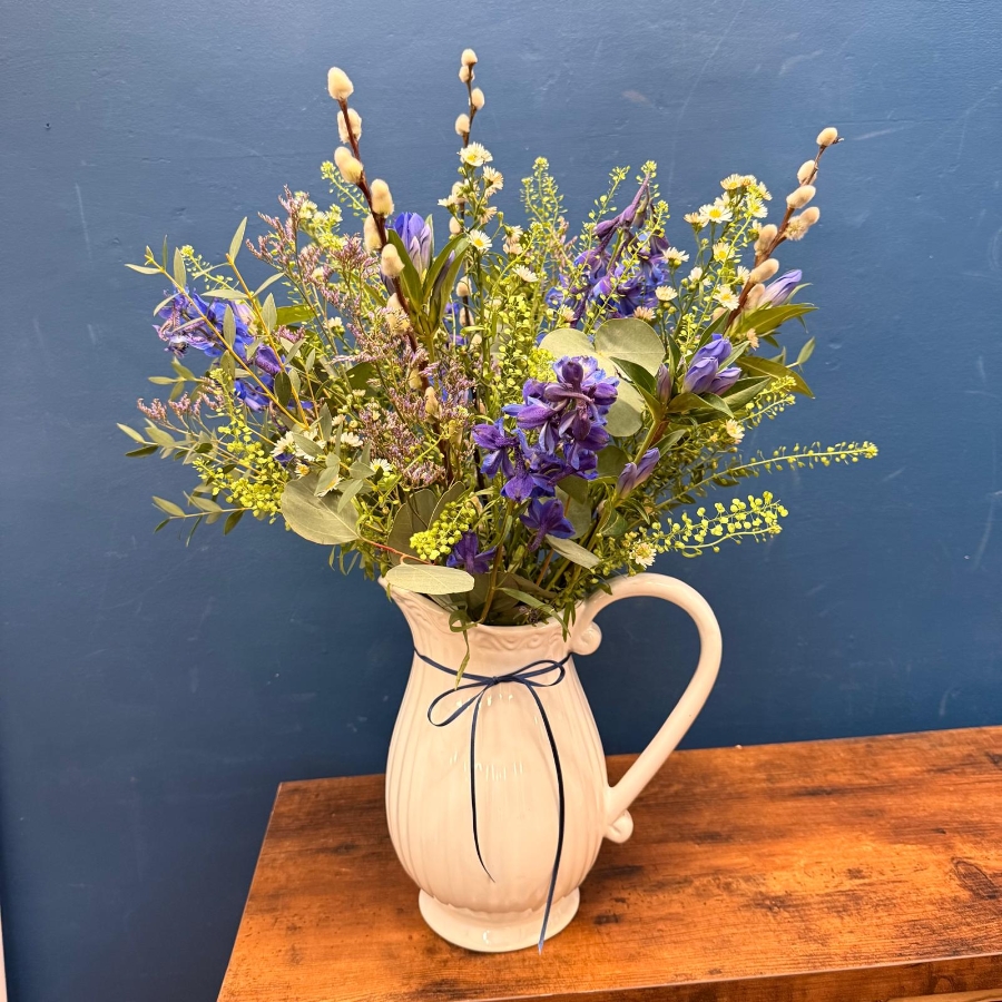 Spring flowers arranged in a white ceramic jug with pink and lilac seasonal flowers