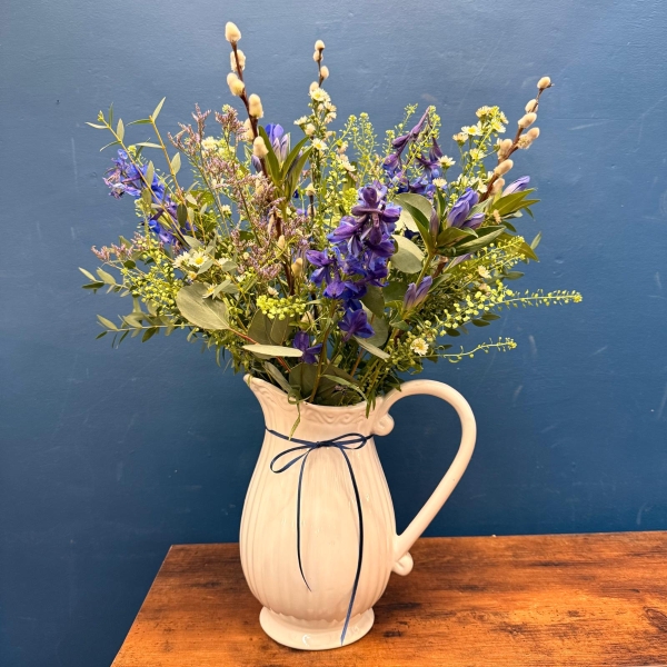 Spring flowers arranged in a white ceramic jug with pink and lilac seasonal flowers