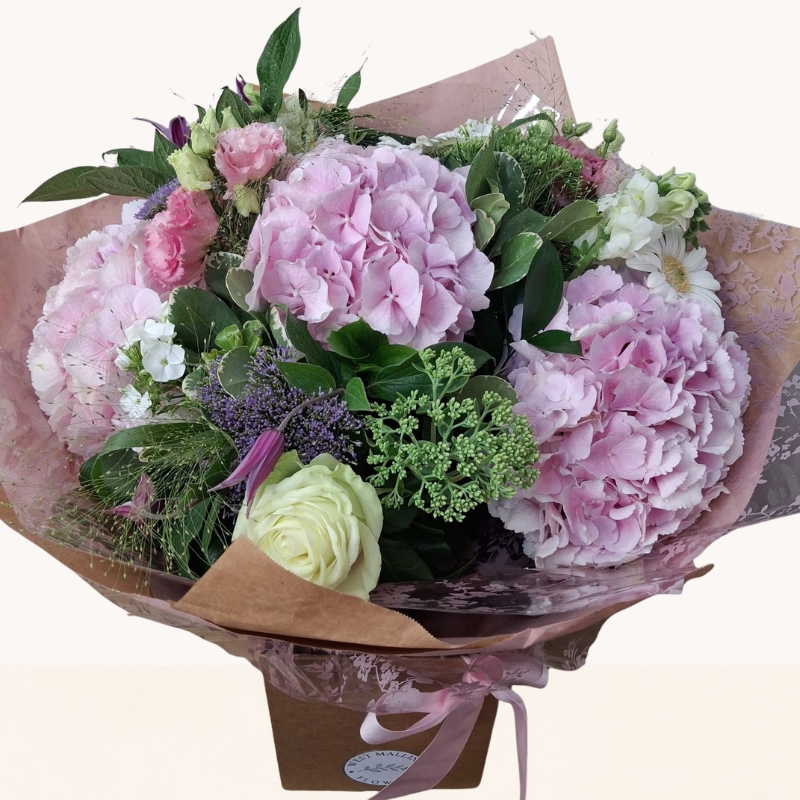 Luxury bouquet of pink hydrangeas with seasonal white and lilac flowers in a soft pastel colour palette.