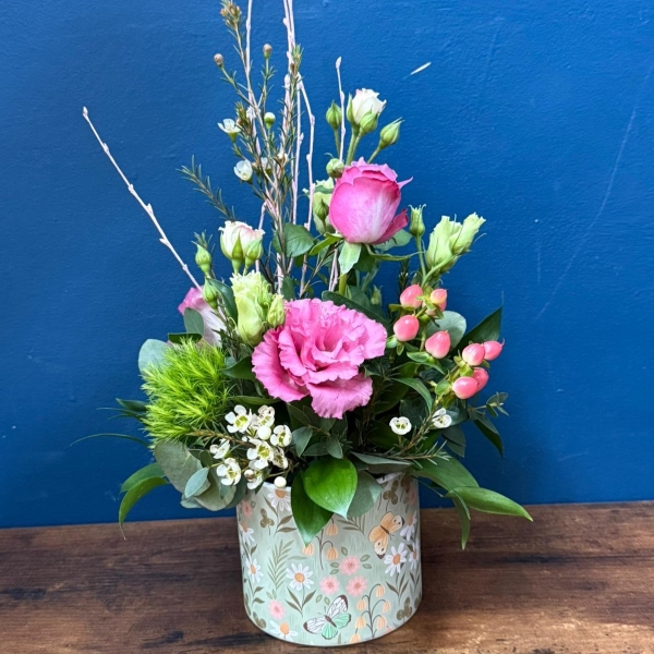 Pink green and white spring flowers arranged in a reusable ceramic pot