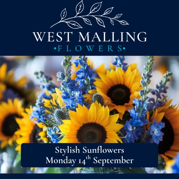 Florist demonstrating a contemporary sunflower arrangement with willow, pine cones and seasonal flowers during a workshop at West Malling Flowers.