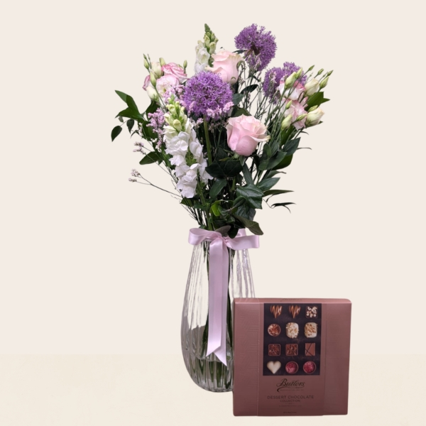 Pastel summer flower arrangement in a glass vase featuring seasonal flowers in soft pink, lilac, cream and white tones.