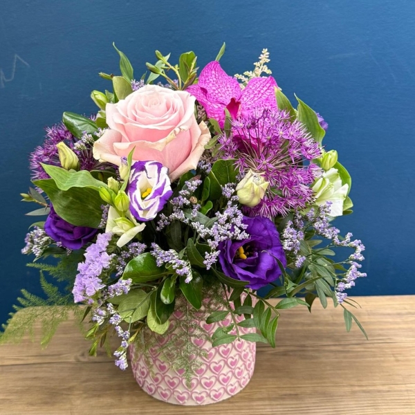 Summer flower arrangement in ceramic clay pot with pink heart design and pastel pink purple flowers