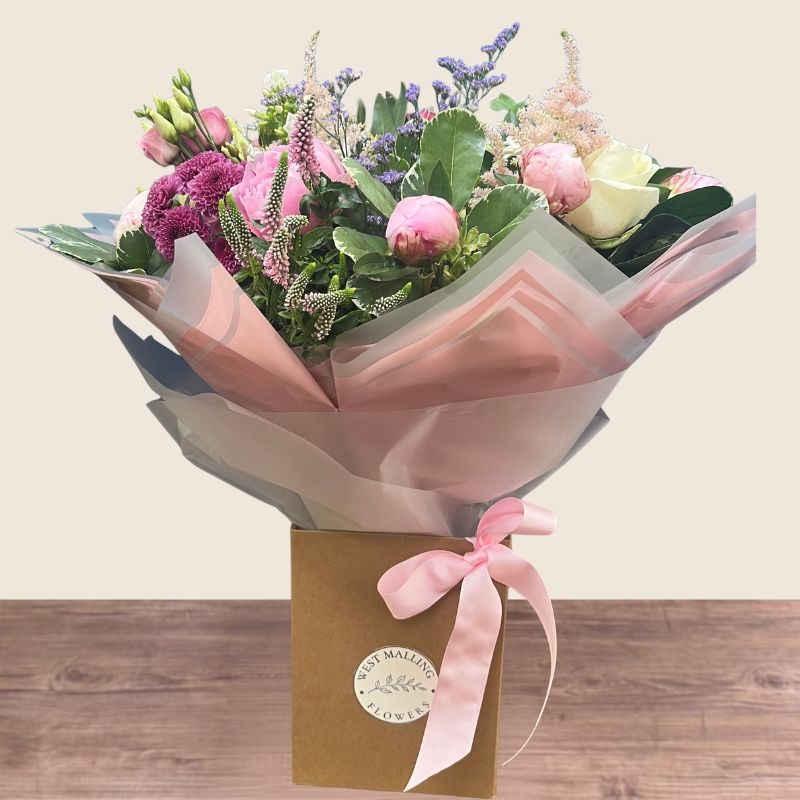 Luxury hand-tied bouquet featuring pink peonies, white flowers and lilac seasonal flowers arranged in a romantic garden style.