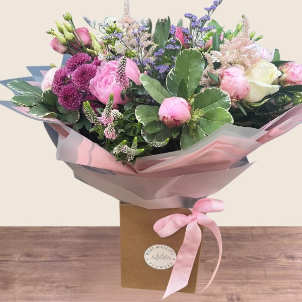 Luxury hand-tied bouquet featuring pink peonies, white flowers and lilac seasonal flowers arranged in a romantic garden style.