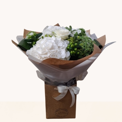 Luxury white hydrangea bouquet with seasonal white flowers and fresh green foliage.