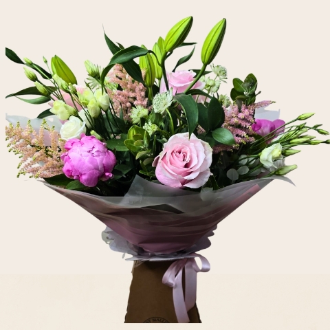 Luxury hand-tied bouquet featuring pink peonies, lilies, roses and seasonal flowers in soft pink, blush and ivory tones.