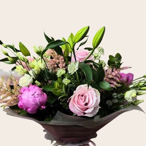 Luxury hand-tied bouquet featuring pink peonies, lilies, roses and seasonal flowers in soft pink, blush and ivory tones.
