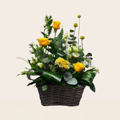 Rustic grey wash basket filled with yellow, white and lemon seasonal flowers, handcrafted by West Malling Flowers.