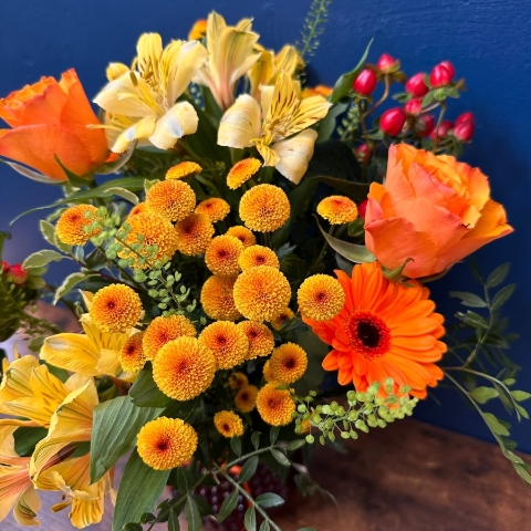 Bright spring vase arrangement with orange yellow and red seasonal flowers in a decorative vase