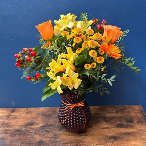 Bright spring vase arrangement with orange yellow and red seasonal flowers in a decorative vase