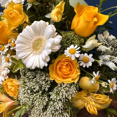 Yellow and white spring flowers arranged in a pale green hat box