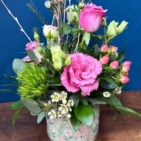 Pink green and white spring flowers arranged in a reusable ceramic pot
