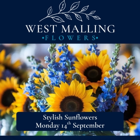 Florist demonstrating a contemporary sunflower arrangement with willow, pine cones and seasonal flowers during a workshop at West Malling Flowers.