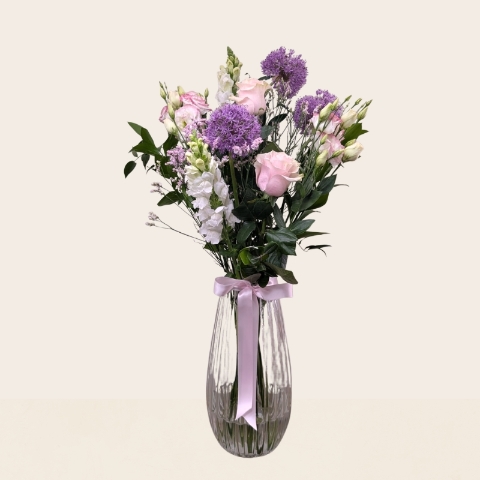 Pastel summer flower arrangement in a glass vase featuring seasonal flowers in soft pink, lilac, cream and white tones.