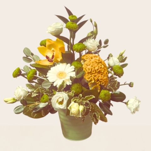 Summer flower arrangement in a zinc pot featuring fresh yellow, lemon and white seasonal flowers with mixed foliage.