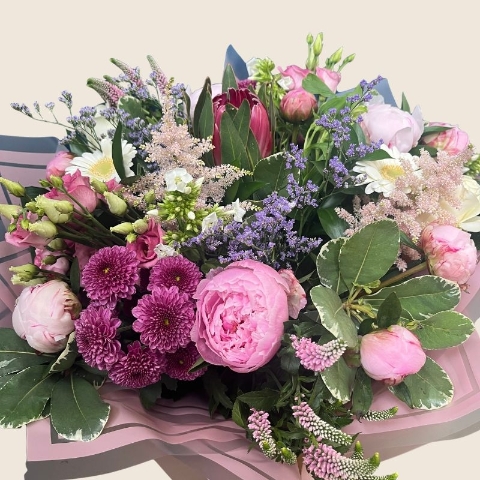 Luxury hand-tied bouquet featuring pink peonies, white flowers and lilac seasonal flowers arranged in a romantic garden style.