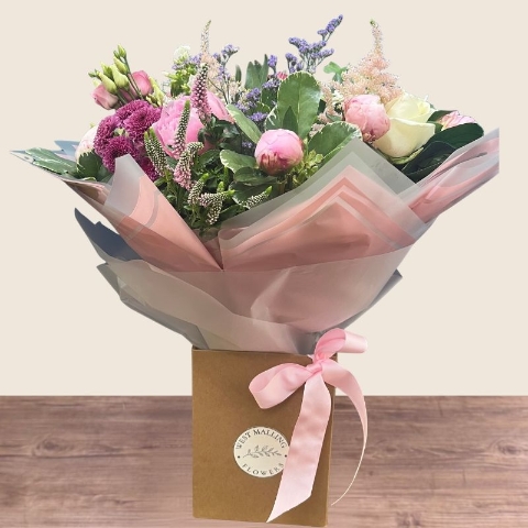 Luxury hand-tied bouquet featuring pink peonies, white flowers and lilac seasonal flowers arranged in a romantic garden style.