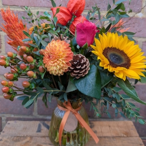 Autumn Glow yellow glass vase arrangement with orange, raspberry, bronze and golden seasonal flowers